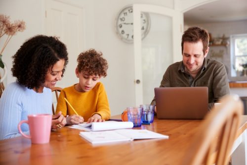 Two parents study with their child at the family table.