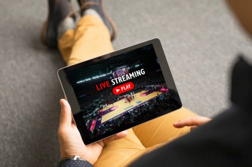 A man watching a basketball game streaming live on a tablet.