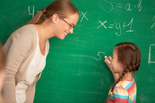 A math teacher helps a student solve a problem.