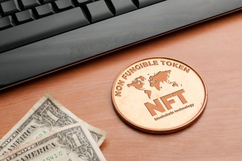 A symbol of a NFT coin next to a keyboard and money.