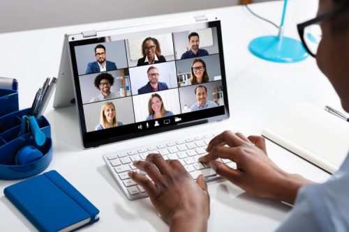 A manager leads a remote team meeting on their laptop.